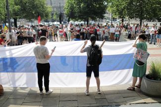 Члены российской диаспоры с антивоенным флагом на марше к посольству России в Варшаве. 12 июня 2022 года