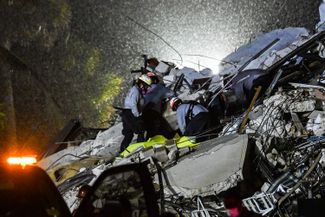 Спасатели поднимают тело погибшего из развалин, 24 июня 2021 года