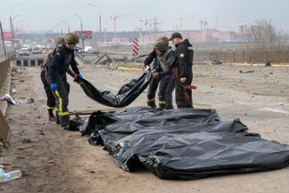 Украинские солдаты собирают тела мирных жителей, погибших у разрушенного моста в Ирпене, Киевская область