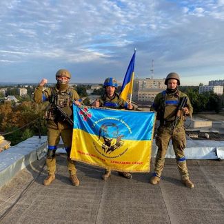 Украинские солдаты с флагами на крыше одного из зданий в освобожденном ВСУ Купянске Харьковской области. Город находится в 117 километрах от Харькова