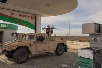 Член команды «охотников за дронами» в составе ВСУ стоит в кузове американского пикапа Humvee