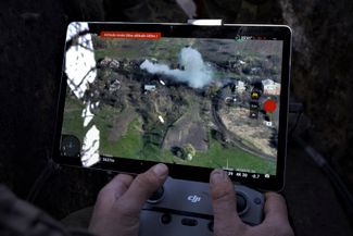 Военнослужащий тактической группы «Адам» управляет дроном. На экране монитора видны клубы дыма над пораженной целью