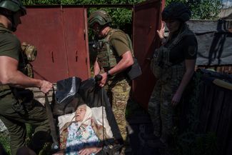 Бойцы спецподразделения украинской полиции «Белый ангел» эвакуируют жительницу Торецка в более безопасное место. Донецкая область, 28 июня 2024 года