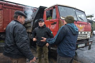 Игорь Дударь (в центре) договаривается с рабочими и водителями в Херсоне о доставке дров в Чернобаевку