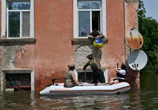 Служащие Национальной гвардии Украины передают еду жителям затопленной части Херсона