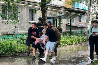 Добровольцы помогают эвакуировать пожилую женщину, получившую ранение. 17 июня 2024 года