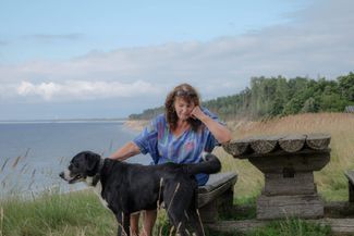 Anna Rudīte Andersone sits by the cliff near her home. July 2024.