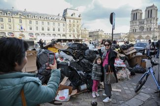 Tourists take pictures in front of a giant garbage dump in central Paris